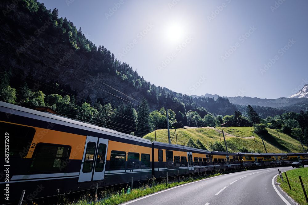 Yellow-green train running through the Swiss Alps.