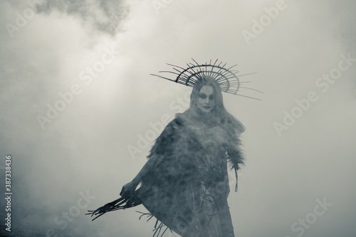 Tela Woman in image of witch stands against smoke background.