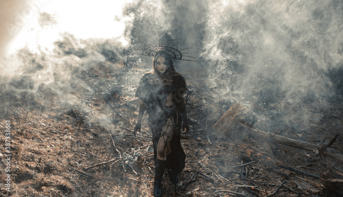 Woman in image of witch walks across foggy forest.