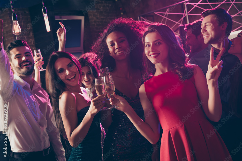 Photo portrait of girl clinking champagne glasses showing v-sign at big christmas party
