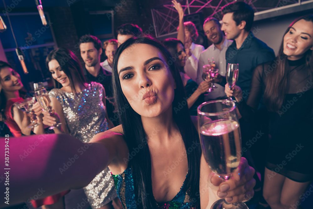 Self photo portrait of girl sending air kiss drinking champagne at luxury party