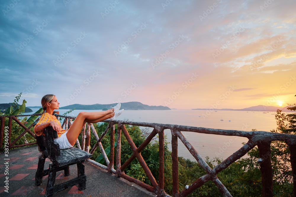 Traveling by Thailand. Young woman enjoying wonderful sunset on Phuket island view point.