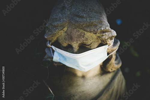 Ancient statue of beautiful angel in medicine respirator mask as symbol of coronavirus, air pollution pm2.5, and quarantine concept.