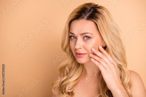 Closeup photo of beautiful lady apply new anti age balm on perfect facial skin wear nothing isolated pastel beige background