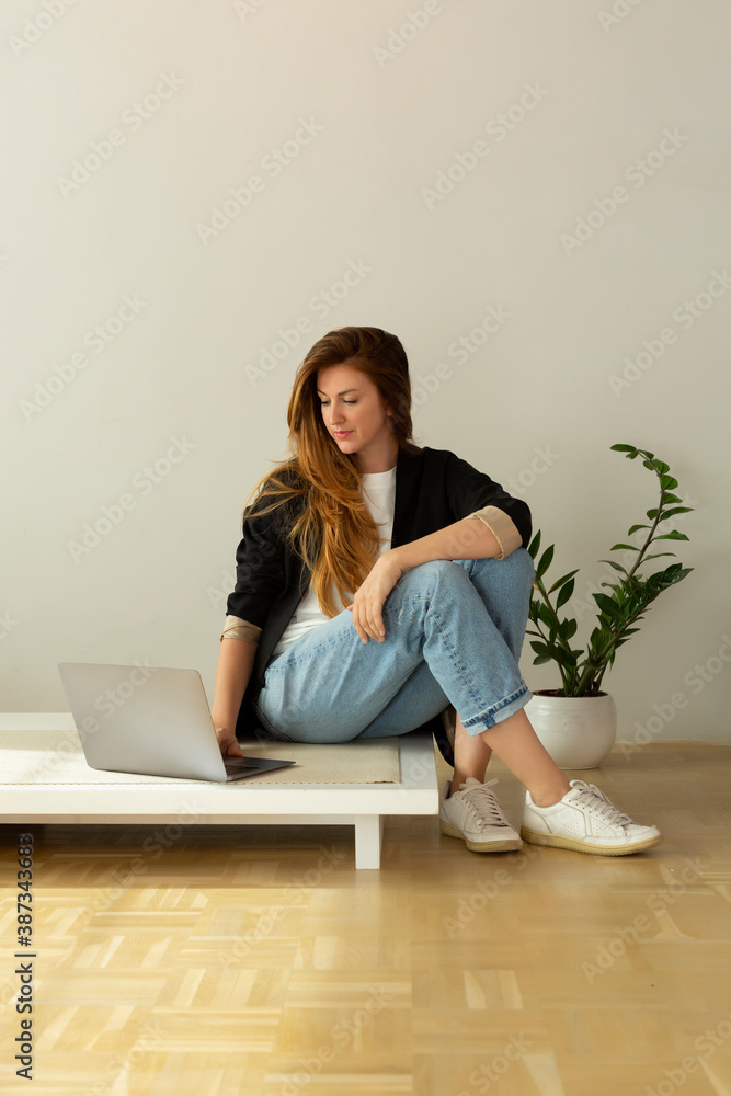 Beautiful woman working on a laptop in minimalist interior apartment Beautiful woman working on a laptop in minimalist interior apartment