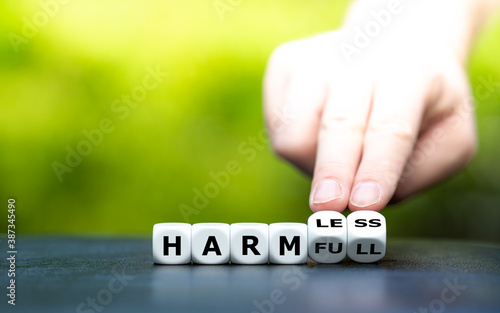 Hand turns dice and changes the word "harmful" to "harmless".