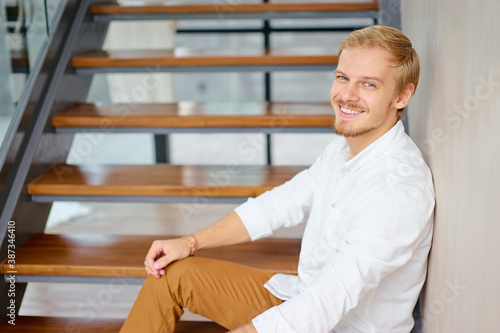 Portrait of young handsome man sitting on stairs.