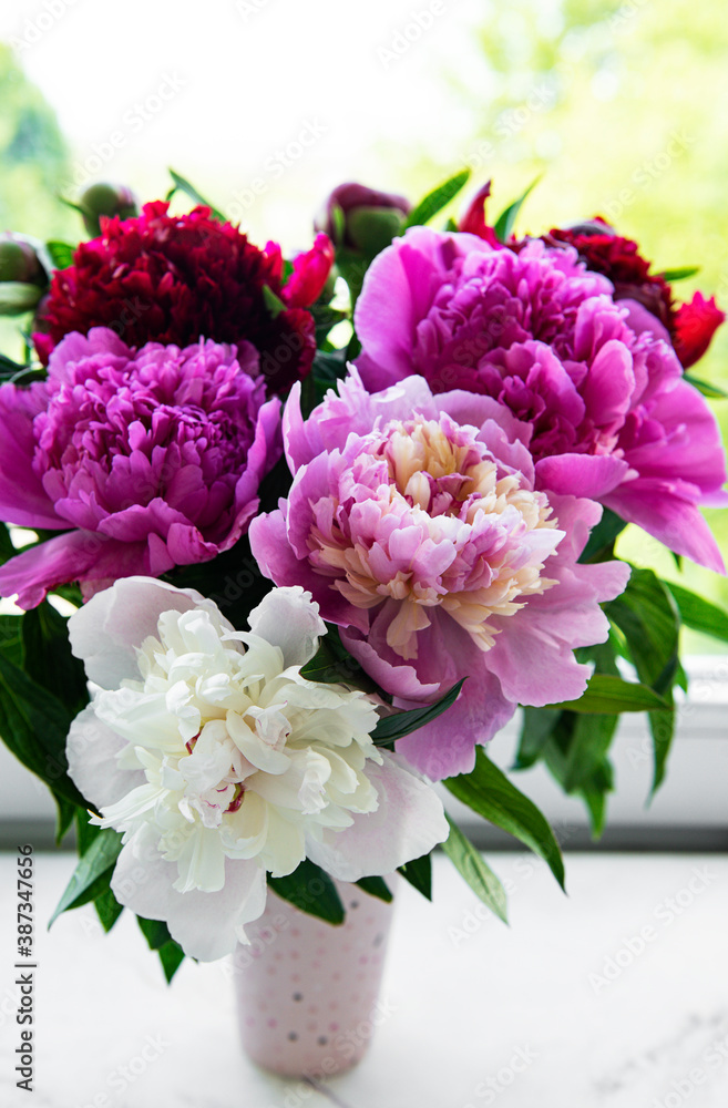 Bouquet of pink peonies in a vase on a wooden table.