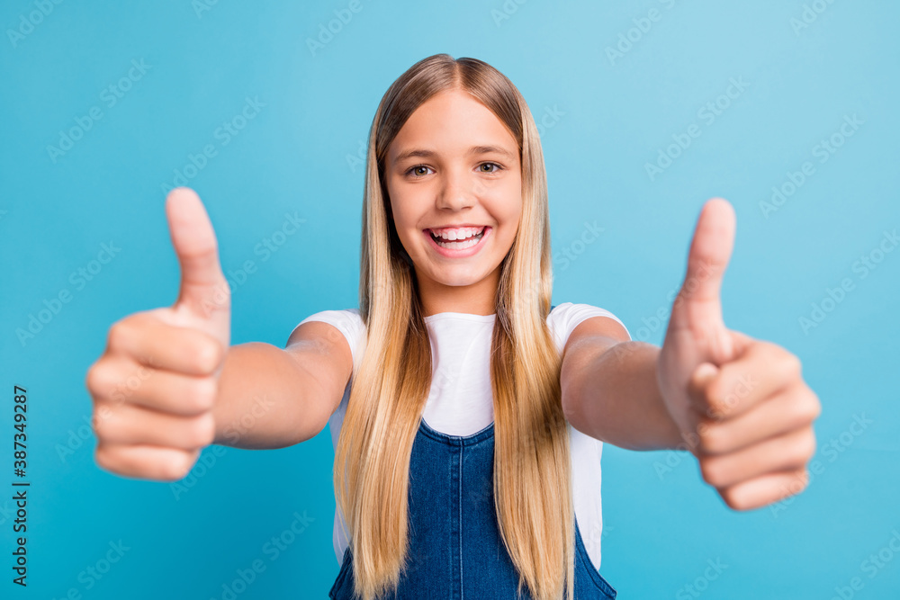 Close up photo of pretty optimistic teen blond long hair girl thumbs up wear white t-shirt isolated over pastel blue color background Close up photo of pretty optimistic teen blond long hair girl thumbs up wear white t-shirt isolated over pastel blue color background