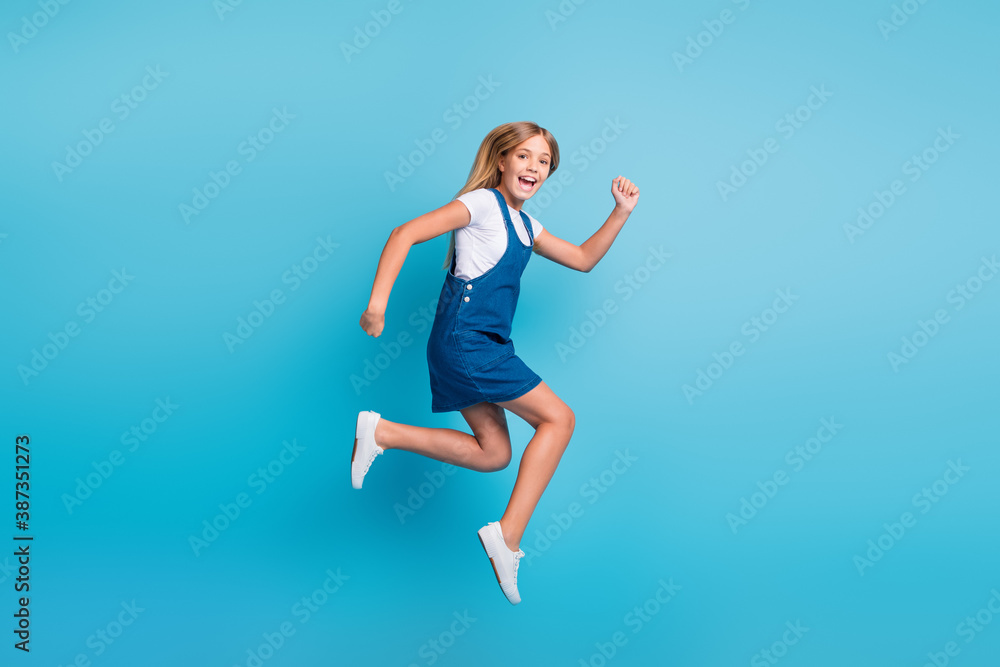 Full size photo of cheerful funny blond girl jumping run wear t-shirt mini dress sneakers isolated on pastel blue color background Full size photo of cheerful funny blond girl jumping run wear t-shirt mini dress sneakers isolated on pastel blue color background