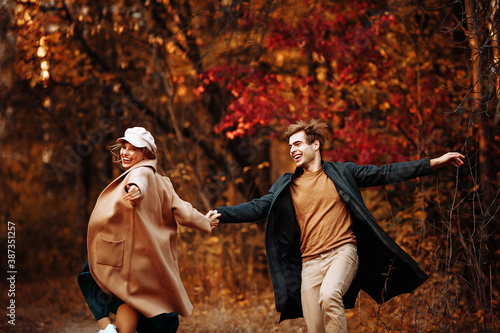 couple in love laughs and walks in the fall in the park, in the forest, yellow leaves. meeting and date. first love. couple jumping