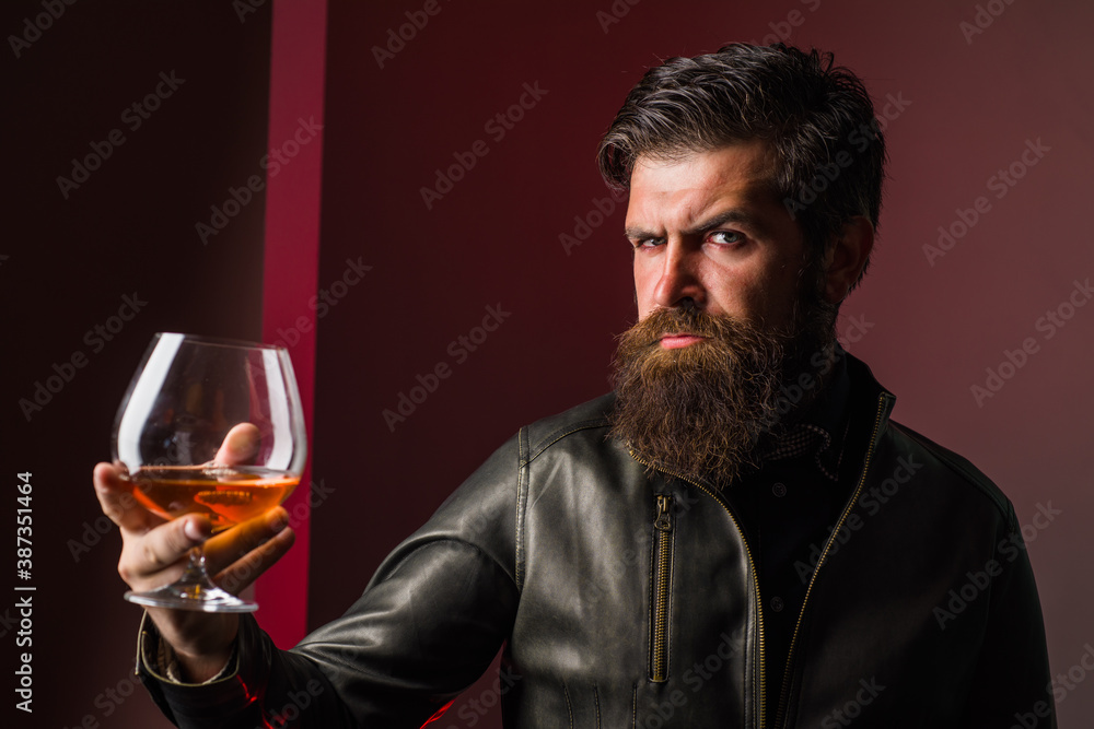 Sommelier degustates whiskey. Strong alcohol. Brutal man drinks whiskey. Degustation and tasting. Man in leather jacket drinks whiskey. Sommelier degustates whiskey. Strong alcohol. Brutal man drinks whiskey. Degustation and tasting. Man in leather jacket drinks whiskey.
