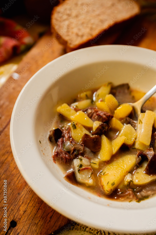 Simple soup in country style with potatoes, meat and mushrooms. Selective focus. Shallow depth of field.