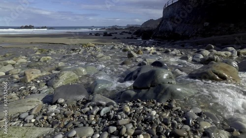 Close-up of river water flowing into a beach and into the sea. Detail of the sand, and the water glistening in the sun