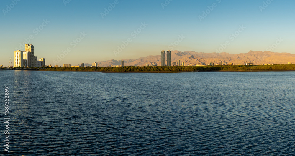 Ras al Khaimah, United Arab Emirates Corniche panorama view to Hajar Mountains and Towers at sunset.