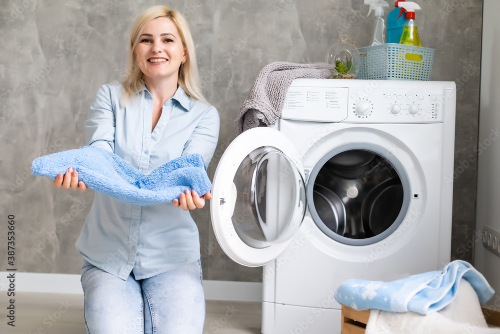 A young housewife with washing machine and clothes. Washing day. A young housewife with washing machine and clothes. Washing day.