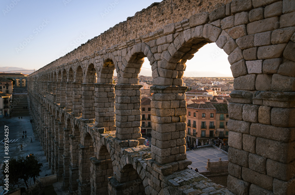 Perspective view of the roman aqueduct in the city center of Segovia at sunset, Spain