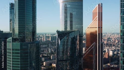 Moscow city glass skyscrapers drone zoom in close to the buildings. Famous Moscow International Business Center sunny evening time, blue horizon line on the background