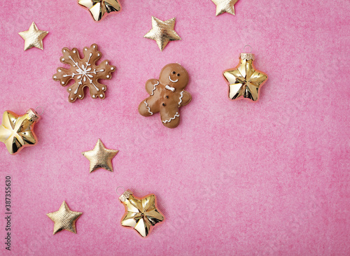 shiny golden christmas ornaments and gingerbread cookies on paper pink background