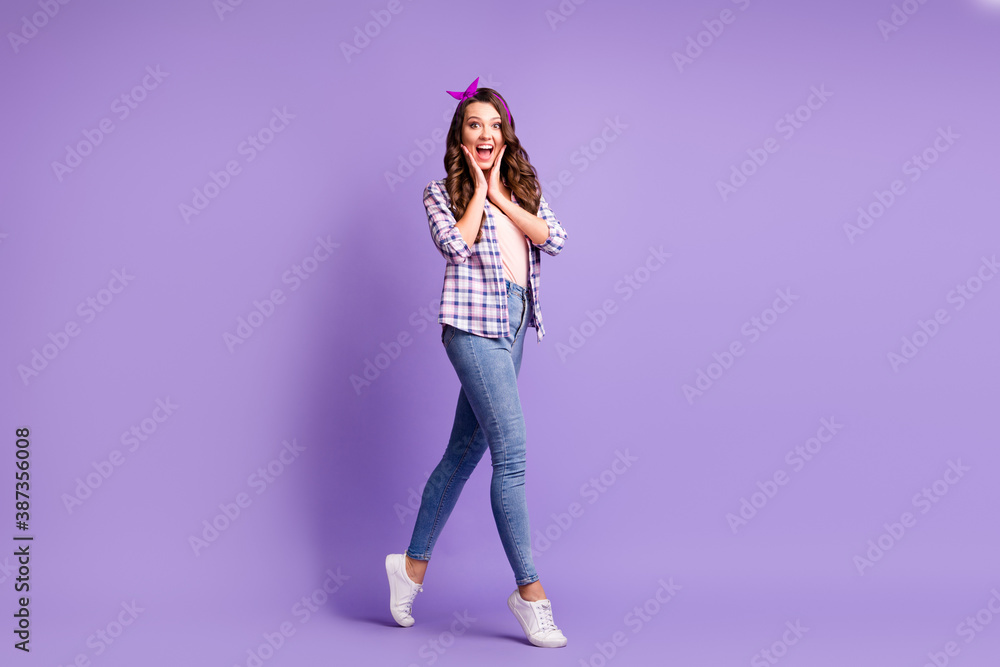 Full length profile photo of lady open mouth tiptoes wear checkered shirt headband jeans sneakers isolated violet color background Full length profile photo of lady open mouth tiptoes wear checkered shirt headband jeans sneakers isolated violet color background