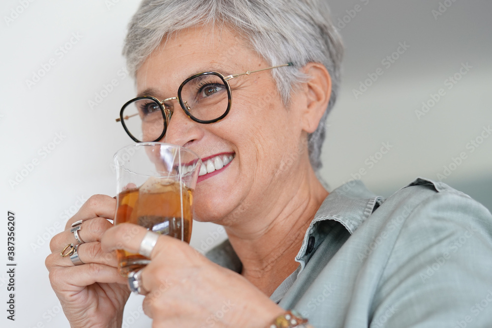 Cheerful 50-year woman drinking hot tea at home Cheerful 50-year woman drinking hot tea at home