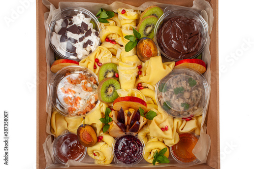 Delivery of food in a box, delicious and fresh food. Convenient boxing for eating at home, at work, in nature. Beautiful pancakes with fruit, chocolate, salmon