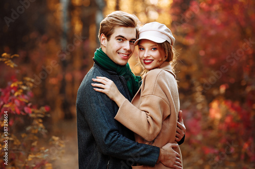 happy, couple in love hugs and smiles on the street, autumn, green scarf and cap, man and woman on a date, valentines day. walk in the park