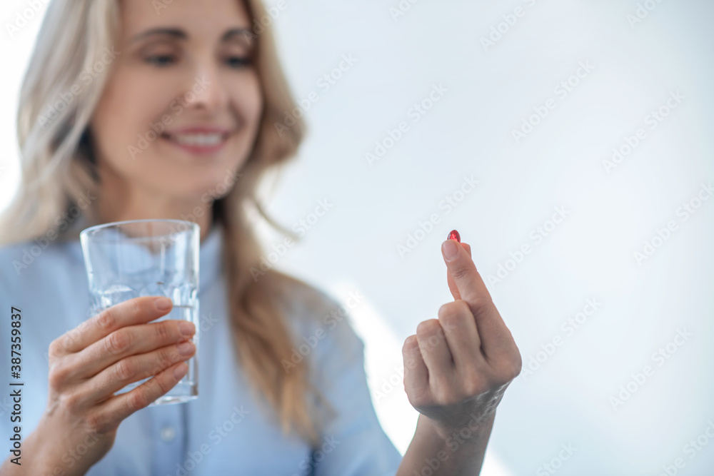 Blonde female holding glass of water, taking red pill Blonde female holding glass of water, taking red pill