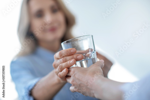 Close-up of female hands giving glass of water to blonde female