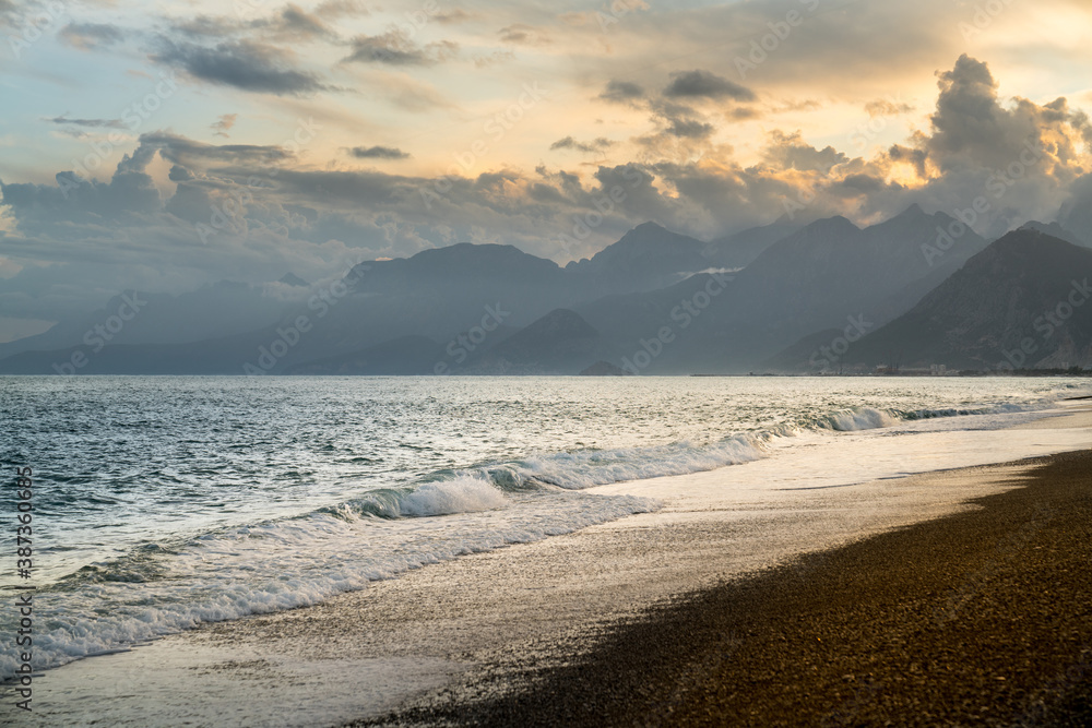 Views at sunset through the clouds above the mountains. Konyaalti beach in Antalya with spectacular Mediterranean sea, Turkey