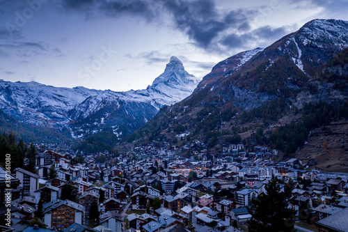 The Swiss village of Zermatt in Valais in autumn at dusk, with the Matterhorn and the Alpine mountain range in the background.