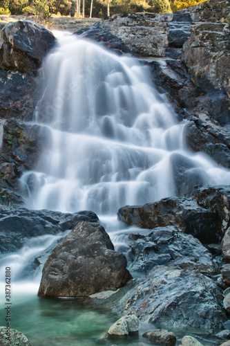 The foaming waterfall that descends between the rocks in the natural park of Mount Avic