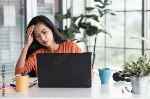 Foto asian woman get stress about project in front of laptop while working from home