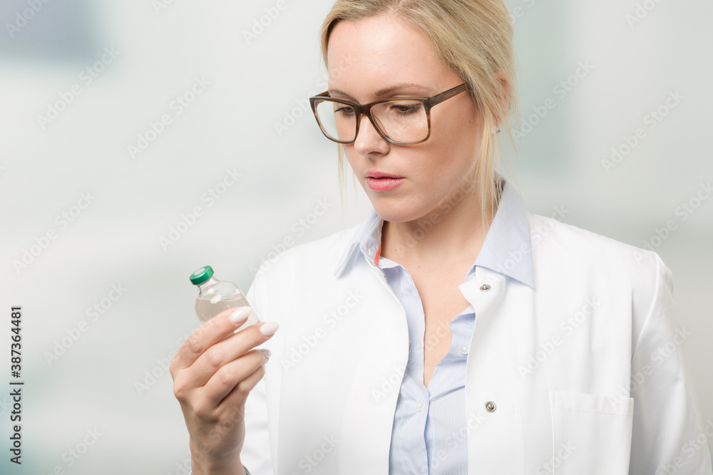 female doctor or nurse is read instructions on a serum bottle with a vaccination serum female doctor or nurse is read instructions on a serum bottle with a vaccination serum