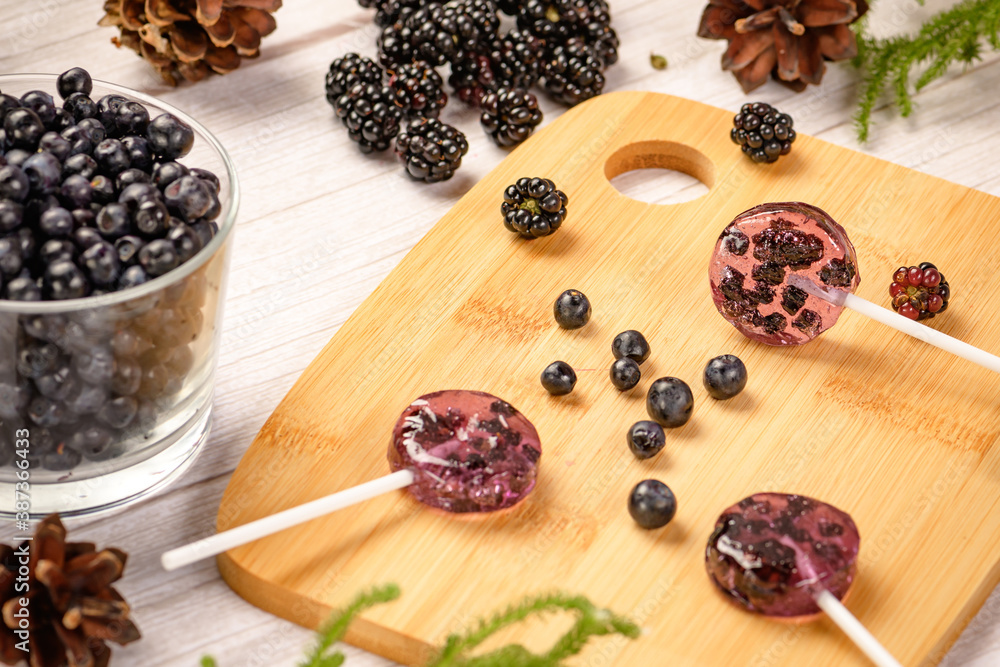 Homemade lollipops made from natural dehydrated bilberry and blackberries on a white wooden background. Healthy vegan vegetarian food with no sweets. Homemade lollipops made from natural dehydrated bilberry and blackberries on a white wooden background. Healthy vegan vegetarian food with no sweets.