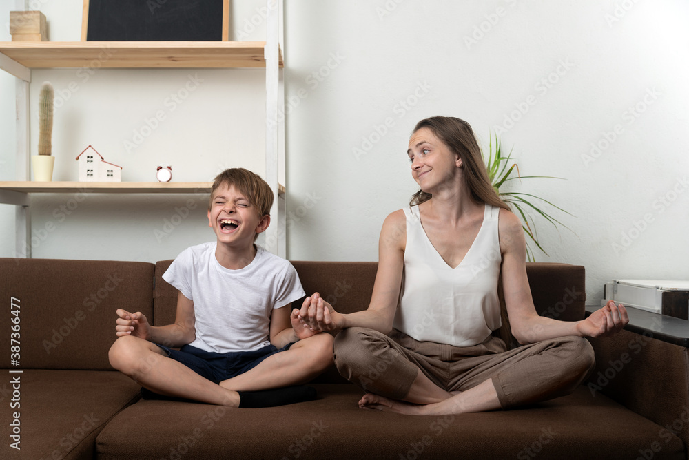 Mom and son fun while practicing yoga sitting on couch. Meditation at home with children.
