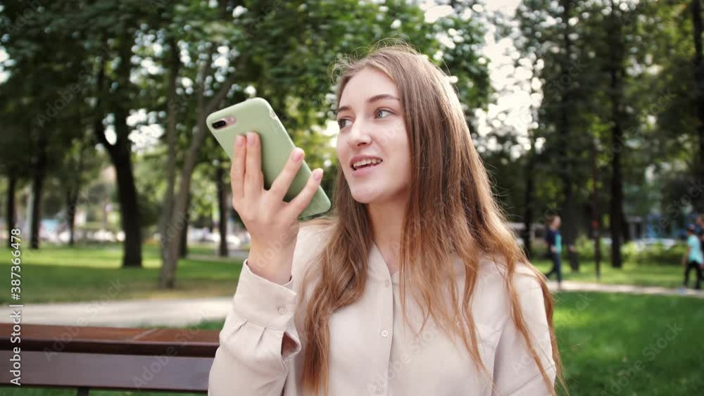 Lady sending audio voice message on smart phone at outdoor talking to mobile assistant. Girl using smartphone voice recognition, dictation message voice Lady sending audio voice message on smart phone at outdoor talking to mobile assistant. Girl using smartphone voice recognition, dictation message voice