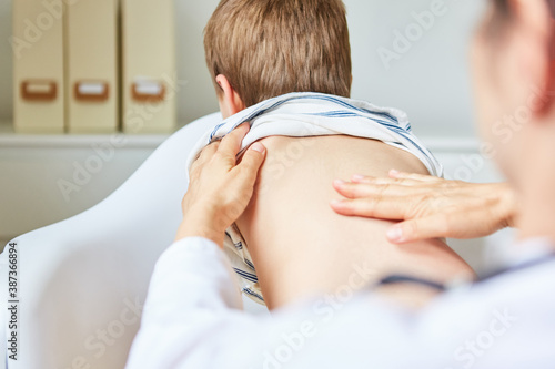 Chiropraktiker behandelt Rücken von Kind mit Hand photo