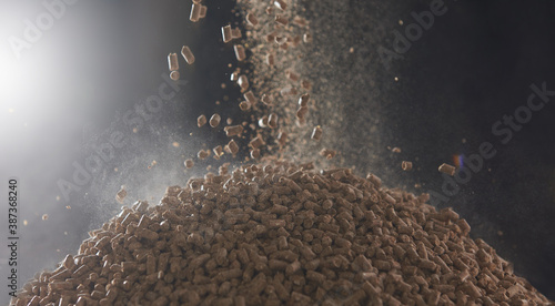Dry compressed animal feed pellets fall into a heap photo