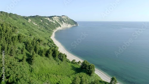 Aerial bird's eye view taken by drone of Mezzavalle beach near Portonovo. The wild beach under a steep cliff with green vegetation reflected in the water is a very famous tourist destination in Marche photo