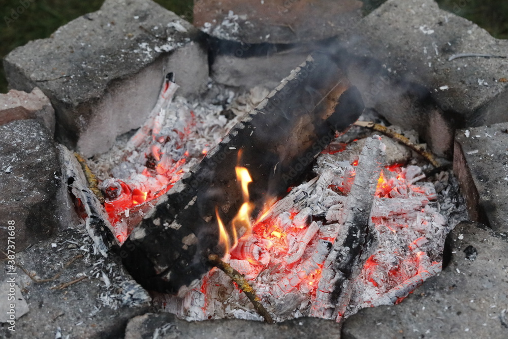 Self made campfire with embers, ashes, stones and coal as close up.