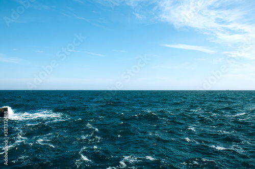 Stormy sea, ocean and blue sky background. Horizon of the sea. Beautiful white clouds on the blue sky