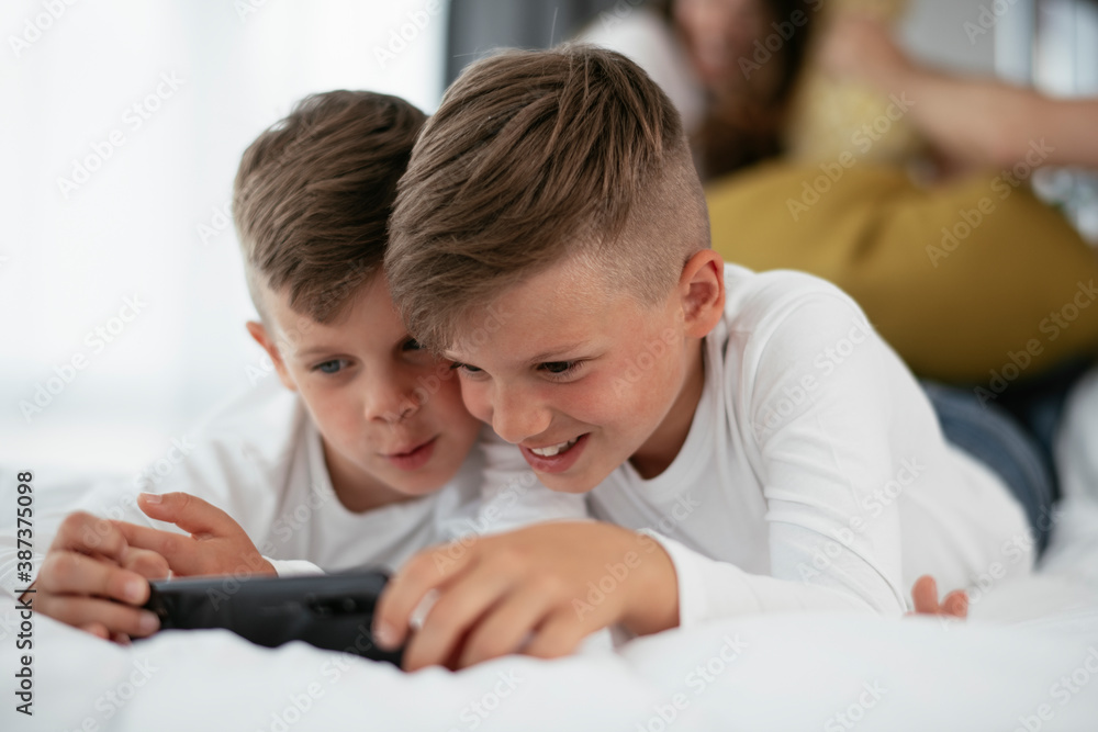 Two little brothers are playing games on the phone. Beautiful boys enjoying at home.. Two little brothers are playing games on the phone. Beautiful boys enjoying at home..