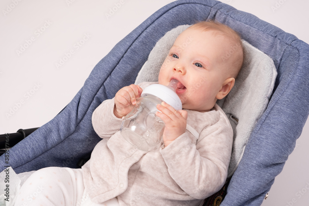 Pretty baby holds a glass bottle for a feeding