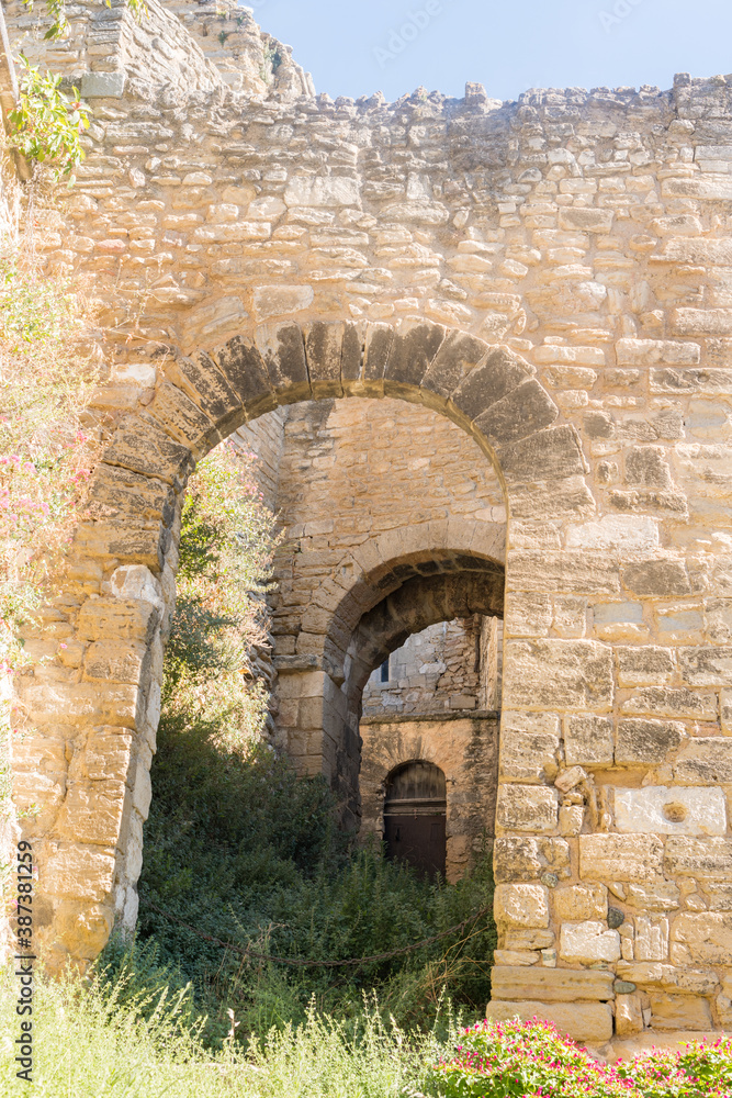 Porte en pierre traditionnelle avec de longs murs et des bâtiments en pierres anciens en ruines dans le Lubéron un jour ensoleillé.