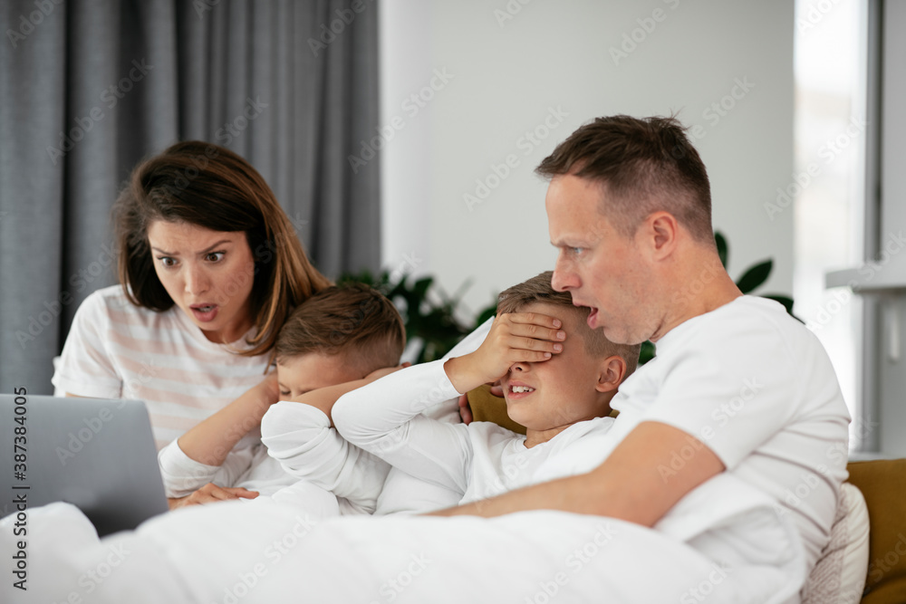 Beautiful parents with kids enjoying at home. Young family watching movie on lap top. Beautiful parents with kids enjoying at home. Young family watching movie on lap top.
