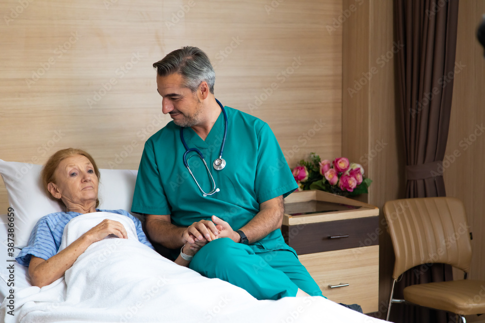 Fototapeta premium Close up of male doctor hands holding senior woman patient hand in hospital bed. comforting and support patient.