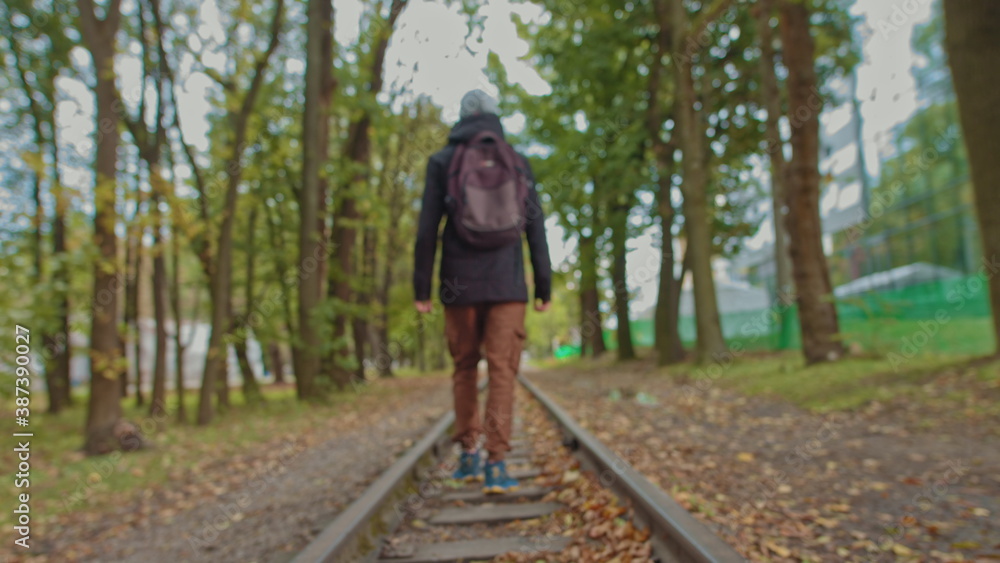 A handsome young man of 18 years in modern warm clothes with a backpack on his shoulders walks on the track, the camera is out of focus. The concept of adolescent loneliness, one in the whole world A handsome young man of 18 years in modern warm clothes with a backpack on his shoulders walks on the track, the camera is out of focus. The concept of adolescent loneliness, one in the whole world