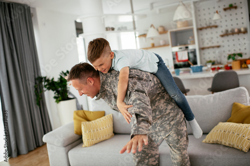Soldier having fun with his son at home. Father and son playing in living room