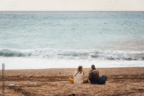 un couple assis sur une plage regardant la mer.